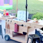 Outdoor party station mobile cart featuring storage for a large cooler, drawer that pulls out and doubles as a serving tray, pipe towel bar, and kiddie table! So COOL!