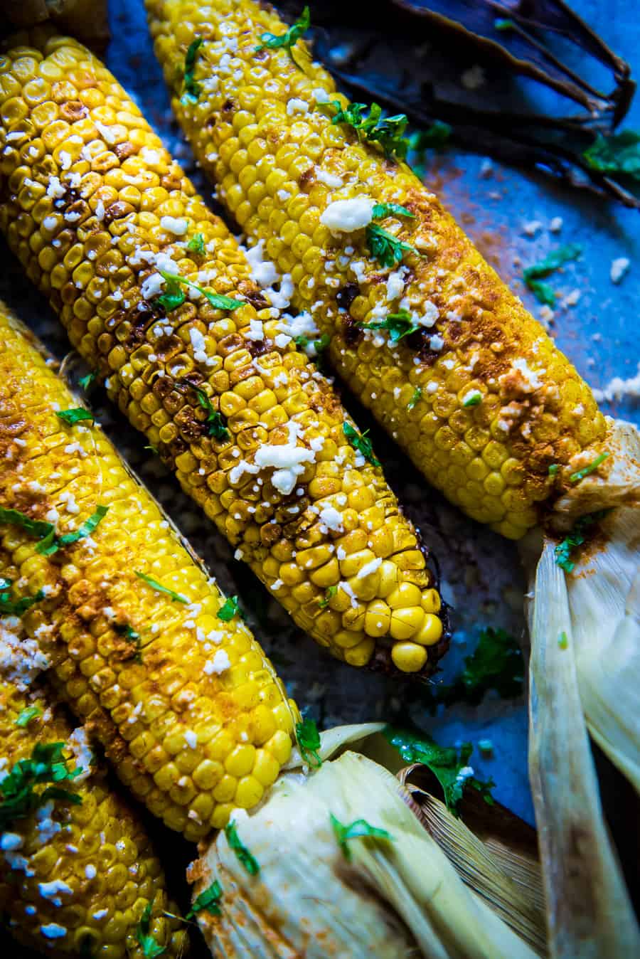 Corn on the cob is coated with juicy butter, finished with chilly powder and fresh cilantro, sprinkled with cotija cheese. Yum!