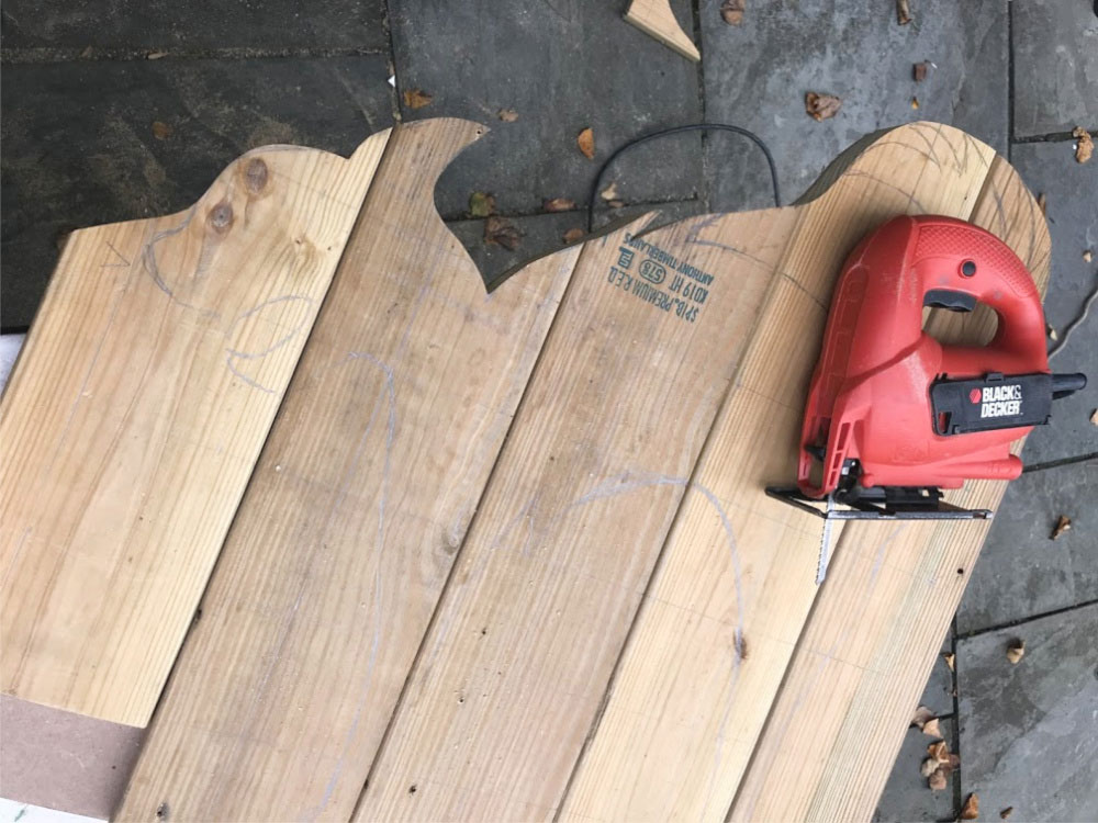 A DIY tutorial to create a large black cat silhouette cut out from wood. Make a statement with a big black cat as part of your Halloween decor. cutting out wood shape with jigsaw