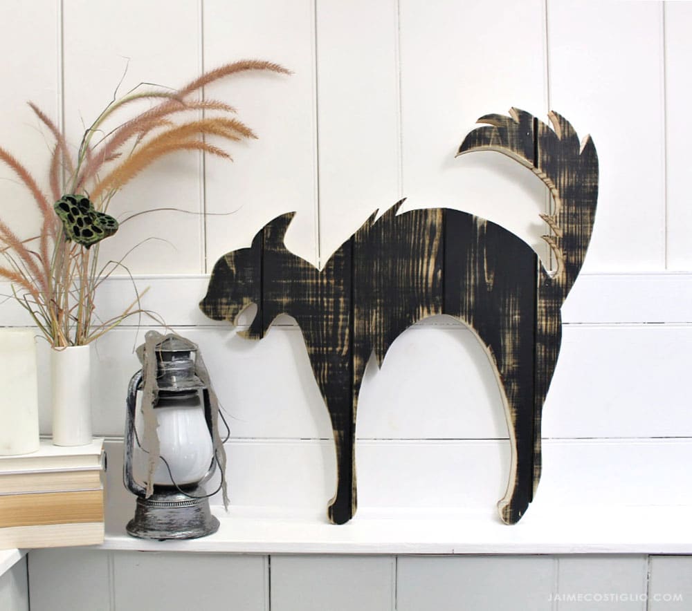 A DIY tutorial to create a large black cat silhouette cut out from wood. Make a statement with a big black cat as part of your Halloween decor. large black cat wood cut out on ledge